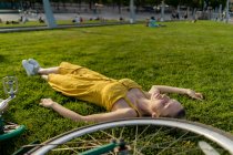 Жінка лежить на траві з велосипедом — стокове фото