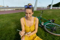 Жінка сидить на траві з велосипедом — стокове фото