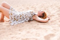 Frau liegt im Sand am Strand — Stockfoto