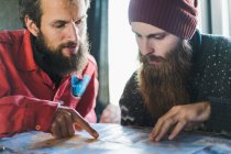 Bearded men pointing on map — Stock Photo