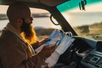 Mann sitzt im Auto und hält Karte — Stockfoto