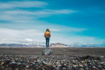 Rückansicht einer jungen Frau, die in einer atemberaubenden Landschaft steht und die Aussicht genießt, während sie durch Island reist — Stockfoto