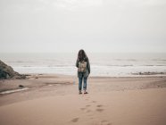 Frau mit Rucksack steht am Meer — Stockfoto