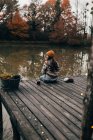 Woman sitting and knitting at pond — Stock Photo