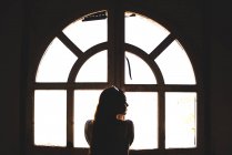 Woman standing next to window — Stock Photo