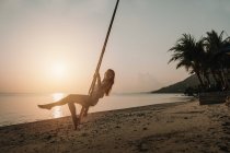 Donna che oscilla sulla spiaggia al tramonto — Foto stock
