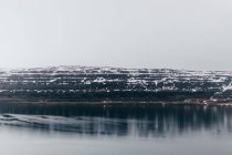 Tranquil water and snowy highlands — Stock Photo