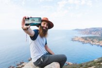 Fröhlicher Mann macht Selfie auf Felsen — Stockfoto