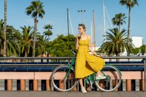 Жінка в літній сукні спирається на велосипед — стокове фото