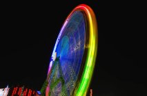 Traces of colorful lights on moving Ferris wheel on background of dark night sky. — Stock Photo