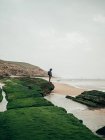 Uomo in piedi su pietra verde all'oceano — Foto stock