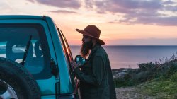 Mann steht vor Auto an der Küste — Stockfoto