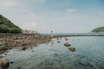 Donna in piedi sulla riva rocciosa — Foto stock