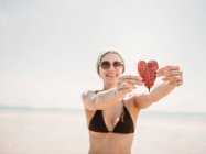 Mulher com folha em forma de coração na praia — Fotografia de Stock