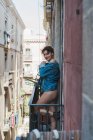 Женщина в джинсовой куртке стоит на балконе — стоковое фото
