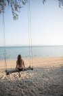 Femme sur les balançoires sur la plage — Photo de stock