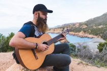 Чоловік грає на гітарі на узбережжі — стокове фото