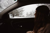 Woman sitting in car in winter forest — Stock Photo