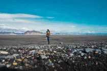 Vista lateral de la joven mujer de pie en el campo increíble y disfrutar de la vista mientras viaja a través de Islandia - foto de stock