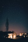 Stone houses illuminated with lamps in rural village under amazing sky with stars at night. — Stock Photo