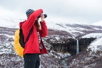 Homme prenant des photos dans un paysage enneigé — Photo de stock