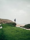 Homme debout sur la pierre verte à l'océan — Photo de stock