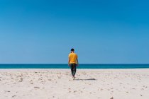 Uomo che cammina sulla spiaggia sabbiosa — Foto stock