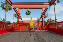 Жінка в літньому одязі спирається на велосипед — стокове фото