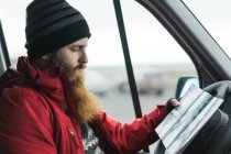 Mann sitzt im Auto und schaut auf Straßenkarte — Stockfoto