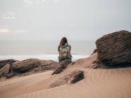 Donna con zaino seduta su roccia — Foto stock