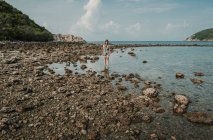 Frau steht am felsigen Ufer am Meer — Stockfoto