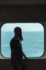 Hombre parado en la ventana en el barco - foto de stock