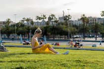 Женщина сидит на траве со смартфоном — стоковое фото