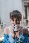 Mulher encaracolado com xícara de café na varanda — Fotografia de Stock