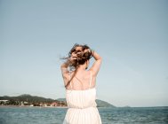 Femme ajustement des cheveux au bord de la mer — Photo de stock