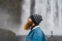 Людина стоїть перед водоспадом — стокове фото