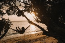 Женщина отдыхает на гамаке в море — стоковое фото