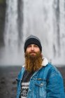 Людина стоїть перед водоспадом — стокове фото