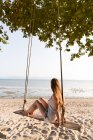 Donna seduta su altalene sulla spiaggia — Foto stock