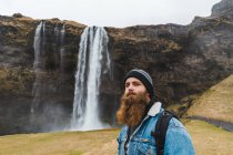 Uomo in piedi di fronte alla cascata — Foto stock