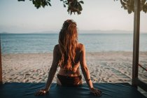 Женщина сидит на песчаном солнечном пляже — стоковое фото