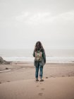 Woman with backpack standing at ocean — Stock Photo