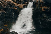 Wasserfall fließt aus düsteren schwarzen Felsen — Stockfoto