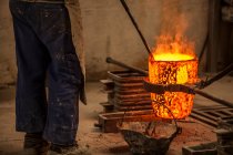 Schnittansicht eines Mannes in Arbeitskleidung, der mit brennendem Feuer Kohlen im Ofen verhindert — Stockfoto