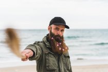 Человек с палкой и цветами в бороде — стоковое фото