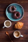 Cups of coffee and fresh croissant with donuts — Stock Photo
