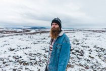 Bearded man walking on snowy field — Stock Photo