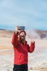 Homme debout avec smartphone chez geyser — Photo de stock