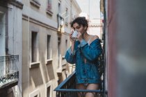 Frau in Jeansjacke steht auf Balkon — Stockfoto