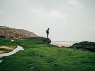 Uomo in piedi su pietra verde all'oceano — Foto stock